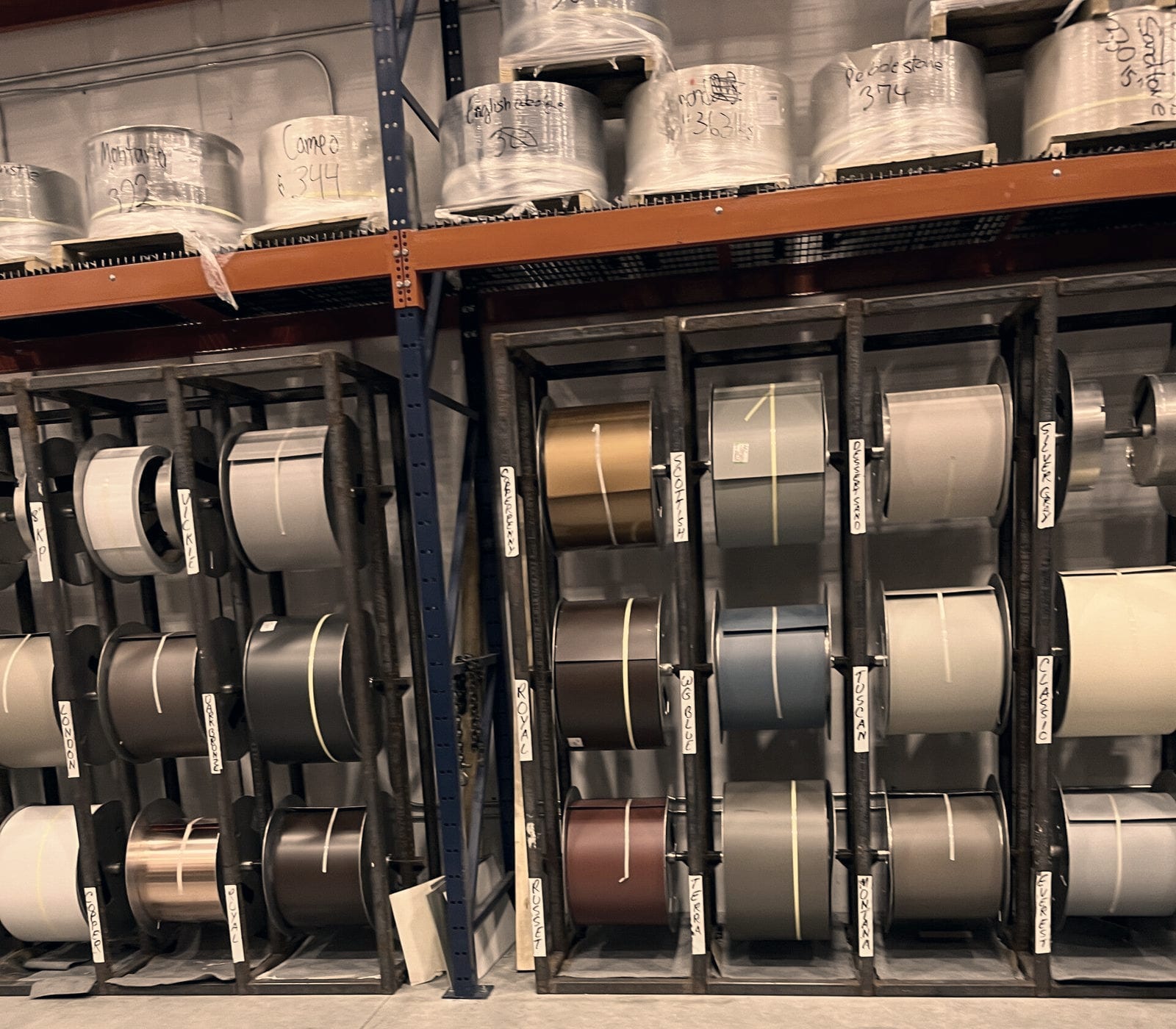 Racks of coated aluminum coil stock, each roll hand-labeled with its color name.